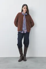 Cardigan de textura suave y efecto fluffy, color beige, con cuello redondo, cierre frontal con botones y puños acanalados.