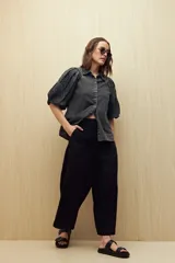 Pantalón de lino color negro, de tiro alto y corte wide leg con pierna ancha y caída fluida.