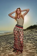 Falda larga tejida a crochet con diseño de red y patrón de rombos en colores negro, rojo y blanco. Presenta una cintura elástica tejida en color negro.