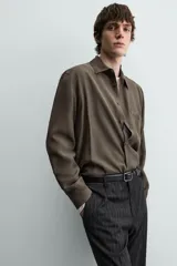 Camisa relaxed fit color verde militar, confeccionada en tejido con mezcla de modal. Tiene cuello solapa, manga larga con puño abotonado, bolsillo plastrón en el pecho y cierre frontal de botonadura.