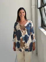 Sweater de tejido de punto con estampado abstracto en tonos azul, marrón y beige. Presenta cuello en V, mangas largas con puños vueltos y un corte holgado.