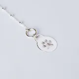 Pulsera de cadena con pequeñas esferas de plata 925, que incluye una medalla circular colgante con el grabado de una huella de mascota.