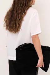 Blusa de lino color beige, de corte recto y mangas cortas, con costuras decorativas pespunteadas en tono rojizo que forman líneas verticales y horizontales.