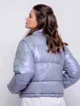 Campera puffer cropped metalizada color plateado, con cuello alto, cierre frontal, dos bolsillos laterales y elástico regulable en la cintura.