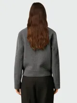 Chaqueta de corte boxy confeccionada en lana gris, con cuello clásico, cierre frontal de botones a tono y diseño minimalista.