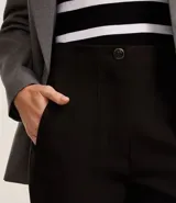 Pantalón zanahoria de sastrería color blanco, con cintura alta, trabillas y botón contrastante.