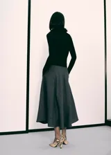 Falda midi de corte evasé en color gris oscuro, confeccionada en tejido mezcla de lana. Presenta tiro alto, cierre de cremallera lateral y bolsillos laterales.