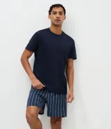 Conjunto de pijama masculino compuesto por una remera de cuello redondo y manga corta en color azul marino liso, y un short con cintura elástica y estampado de rayas verticales en tonos azul y blanco.