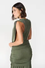 Vestido largo de fiesta color verde oliva, con escote profundo drapeado y falda con frunces laterales que aportan movimiento y caída fluida.