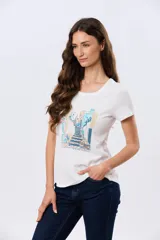 Remera blanca de manga corta y cuello redondo, con estampa frontal ilustrativa de un paisaje urbano con escalinatas en tonos azules y tierra.