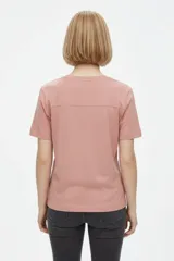 Remera de algodón de manga corta, color blanco, con cuello redondo y estampa frontal de diseño ilustrativo en tonos marrones y fucsia.