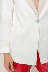 Blazer azul de lino con corte entallado, cuello y solapas combinadas en color gris, cierre con botón de nácar, bolsillos laterales y tajo en la espalda.