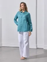 Camisa color verde oliva de lyocell, marca Cyrus. Tiene cuello con solapa, abertura central con botones, mangas 3/4 regulables con presilla y botón, y dos bolsillos delanteros aplicados.