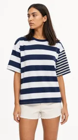 Remera oversize de manga corta con diseño a rayas horizontales en azul marino y blanco, con detalle de patrón de rayas más finas en una de las mangas.