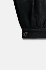 Pantalón bombacho de tiro medio confeccionado en lino, color negro, con pernera abullonada y bajo acabado en puño con botón.