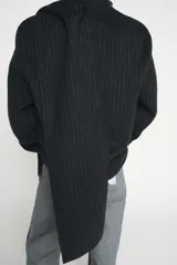 Blazer de corte recto confeccionado en mezcla de lana con estampado de rayas verticales. Presenta cuello redondo con bufanda incorporada en el mismo tejido, manga larga, bolsillos delanteros y cierre frontal con botones.