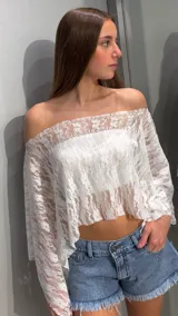 Capa de encaje blanca de corte corto, con diseño transparente, escote bote y mangas anchas y largas.