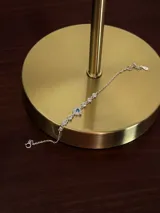 Pulsera de plata 925 con cadena de eslabones finos, decorada con pequeñas zirconias blancas engarzadas y un dije central en forma de corazón con una zirconia celeste rodeada de zirconias blancas.