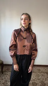 Tapado corto de tafeta marrón con cuello mao, mangas abullonadas, puños anchos y cierres de estilo oriental con detalles de encaje negro.