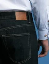 Pantalon denim de corte recto y cinco bolsillos, con cierre de botones y remaches metálicos en tono plata viejo.