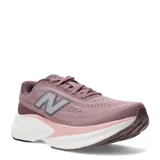 Championes New Balance Kaiha de mujer, color rosado con entresuela blanca y rosada clara, y suela marrón. Presenta el logotipo "N" característico en los laterales.