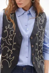 Chaleco marrón de simil cuero con bordado en color crema, cuello en V y cierre frontal con botones.