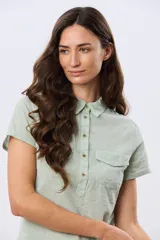 Camisa de lino celeste de manga corta, con cuello clásico, cierre frontal con botones y dos bolsillos frontales con solapa.