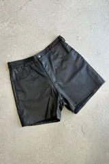 Bermuda de cuero napa negro, de corte recto y tiro alto, con cierre frontal y bolsillos laterales.