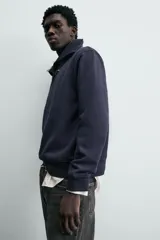 Sudadera de calce relajado color azul marino, con cuello alto y cierre frontal mediante alamares metálicos. Presenta manga larga y terminaciones en rib en puños y cintura.