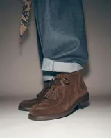 Botas de gamuza color marrón, de caña corta, con cordones, borlas colgantes en el empeine y suela de taco bajo.