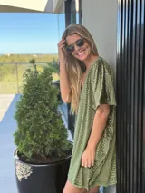 Vestido corto de terciopelo verde con textura de piel de reptil, escote en V y mangas cortas holgadas.