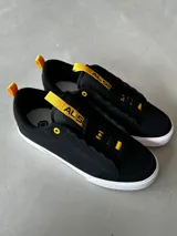 Championes CIRCA 50 PRO EVOLUTION, color negro con detalles en amarillo, de caña baja, con triple costura en la puntera, lengüeta acolchada, cordones ocultos y suela de goma FusionGrip™ vulcanizada.