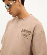 Remera de manga corta confeccionada en gamuza sintética color beige. Presenta cuello redondo y un bordado frontal con lettering estilo gótico y estrellas.