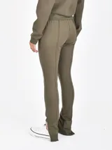 Pantalon deportivo color verde oliva, de corte ajustado con costuras frontales verticales y cierre en los tobillos. Cuenta con cintura elástica con cordón ajustable.