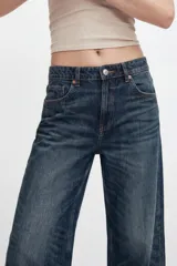 Jeans de mezclilla de tiro medio con cinco bolsillos, diseño relaxed fit de corte recto y amplio, con efecto lavado y desgaste frontal.
