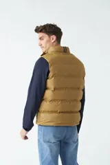 Chaleco color camel de nylon con cierre frontal con broches a presión, cuello alto y bolsillos laterales.