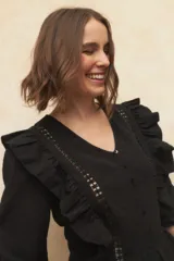 Blusa color verde claro con textura arrugada, escote en V, cierre frontal con botones, mangas 3/4 con puños elásticos y detalles de encaje y volados en el frente y los hombros.