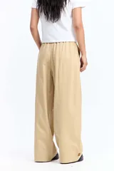 Pantalón de vestir negro de corte wide leg, con cintura elástica ajustable mediante cordón, pliegues frontales y diseño holgado.