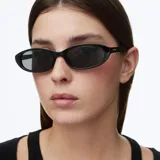 Lentes de sol con montura ovalada de color negro y cristales oscuros polarizados, con diseño minimalista y contemporáneo.
