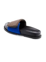 Sandalia tipo slide de cuero, color negro, con tira ancha acolchada en la parte superior y una tira inferior de color fucsia/magenta brillante. La suela es negra con borde dentado. Se observa texto en la plantilla que parece ser 'yuko imanishi+'.