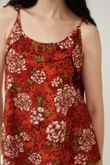 Musculosa color ladrillo con estampado de flores blancas y hojas verdes, breteles finos y escote redondo.