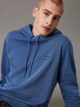 Buzo con capucha Calvin Klein color azul, de felpa de algodón y poliéster. Tiene corte regular, puños y bajo de canalé, capucha con cordón y logo bordado en el pecho.