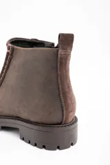 Bota corta de cuero vacuno en tono marrón oscuro, con diseño de costuras visibles en el empeine y suela de goma dentada tipo track.