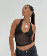 Top halter negro, ajustado al cuerpo, confeccionado en tejido de malla transparente con detalles brillantes o plateados en forma de líneas verticales. Presenta un escote pronunciado en V.