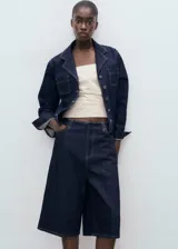 Short de jean de tiro medio con diseño recto, confeccionado en algodón estilo tejano vaquero. Cuenta con cuatro bolsillos y cierre oculto de botón, gancho y cremallera.