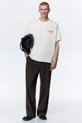 Remera de algodón blanca de corte holgado, con cuello redondo y diseño estampado en el pecho con texto en color rojo.
