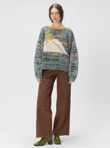 Sweater de punto con diseño geométrico y gráfico frontal en color rojo. Presenta cuello redondo, mangas largas holgadas y un ajuste suelto.