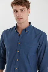 Camisa de vestir blanca de manga larga, con cuello abotonado, bolsillo frontal y botones en tono madera.