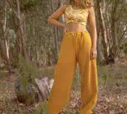 Pantalón de pierna ancha con estampado de hojas en tonos amarillos y marrones, cintura elastizada y bolsillos laterales.