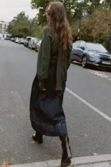 Sweater de punto color verde militar, con cuello asimétrico y manga larga con brazalete metálico en el puño.